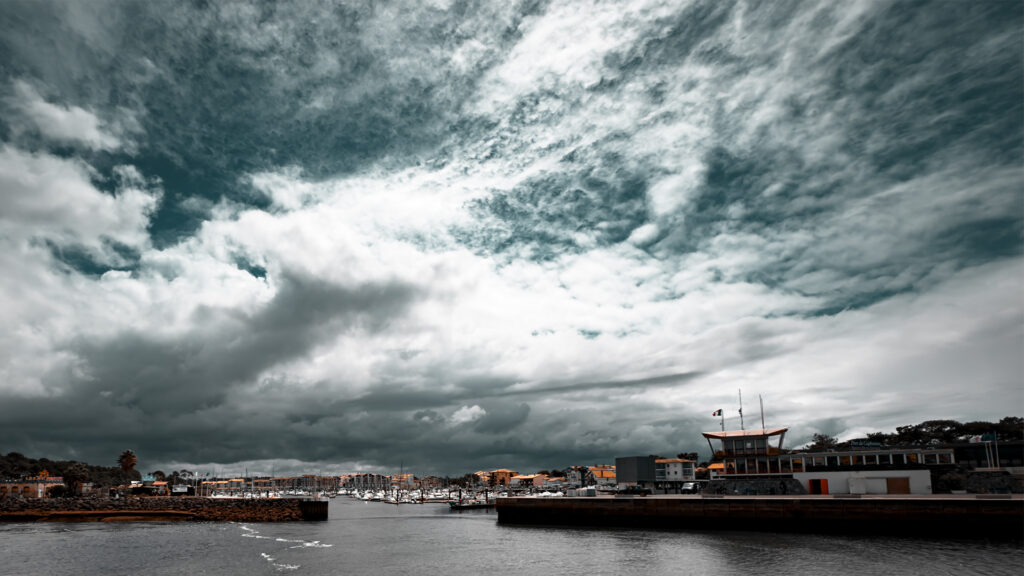 Hafenstadt mit Yachthafen unter dramatischem Himmel – Blick auf Port de Capbreton in Frankreich bei aufziehenden Wolken.