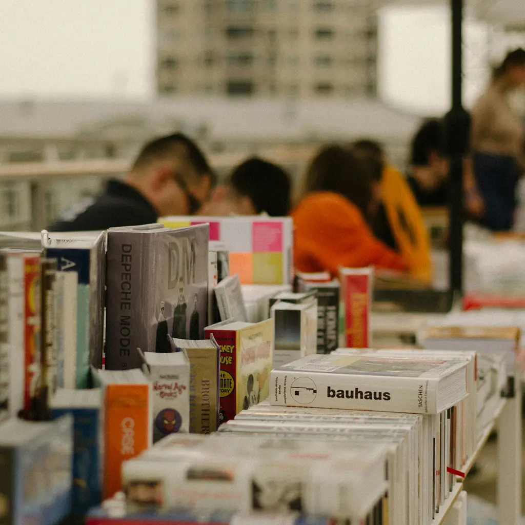 büchertisch auf der Frankfurter Buchmesse, Besucher*innen stöbern zwischen Romanen und Sachbüchern. so könnte es auf der Buchmesse 2025 aussehen