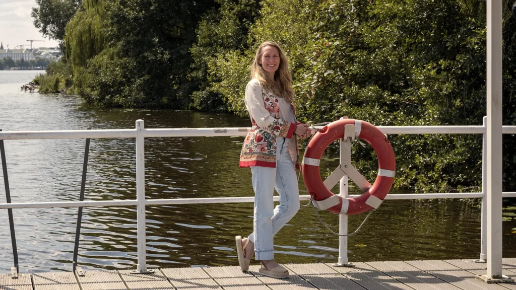Isabella steht entspannt am Wasser neben einem Rettungsring – Symbol für Selbstfürsorge und innere Balance