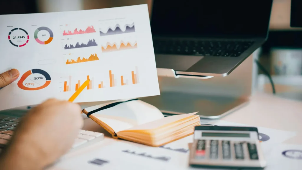 Analyse von Performance Marketing Daten mit Diagrammen, Laptop und Taschenrechner auf einem modernen Schreibtisch