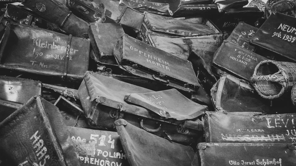 Aufnahme eines Kofferstapels mit Namen und Herkunftsorten von deportierten Menschen – ausgestellt im Museum Auschwitz-Birkenau. Symbolbild zum Holocaust Gedenktag, das an die individuellen Schicksale erinnert.