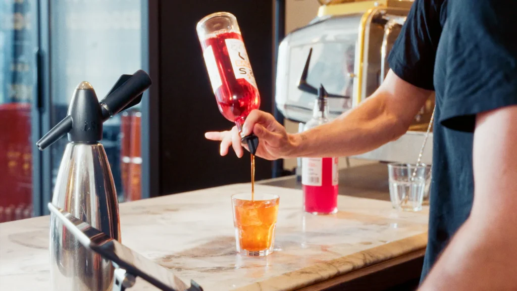 zino's spritz wird frisch an der Bar eingeschenkt – Aperitivo-Drink in einem Glas auf einer Marmor-Theke