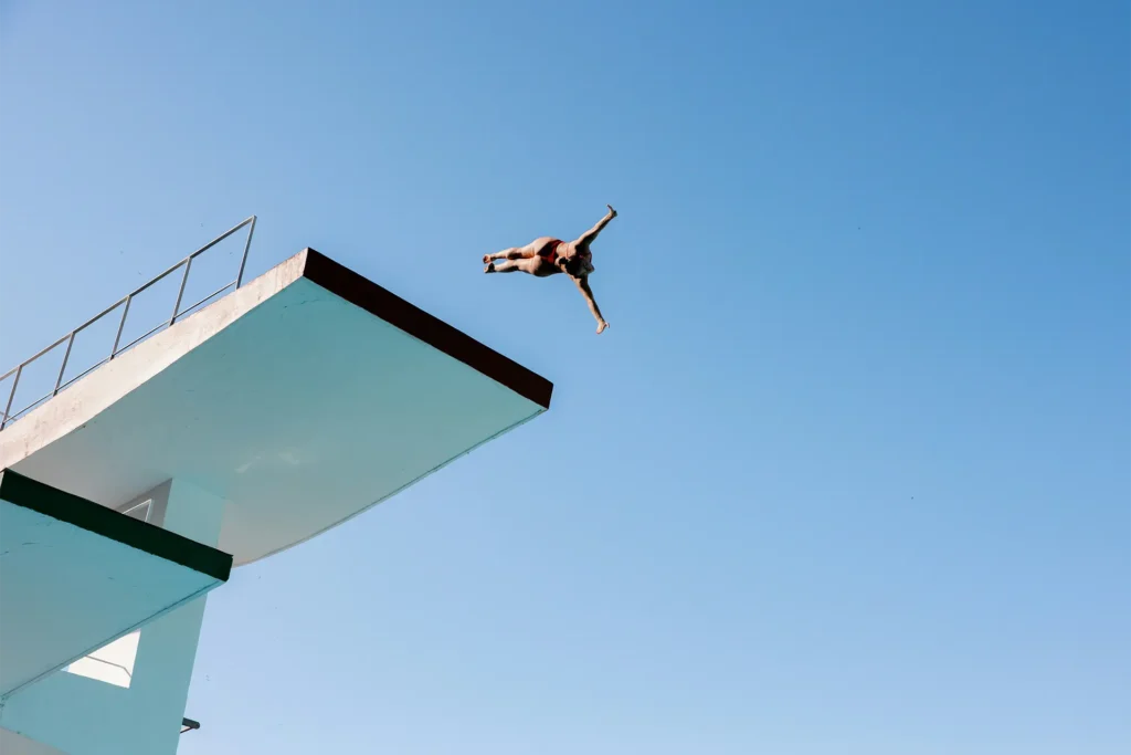 Person springt vom Sprungturm, Symbol für den ersten Schritt bei Sprunginnovation
